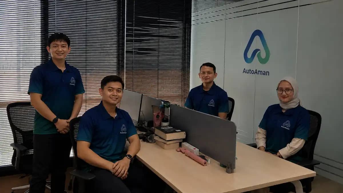 Empat anggota tim AutoAman bersama logo AutoAman