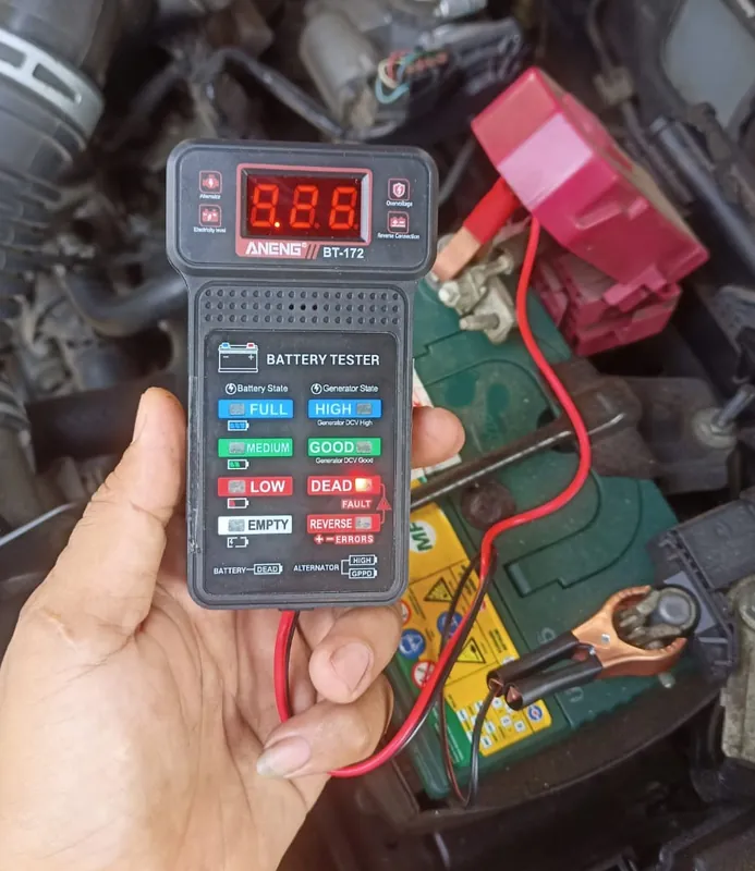 Battery tester dengan kabel pengukuran terhubung ke aki kendaraan