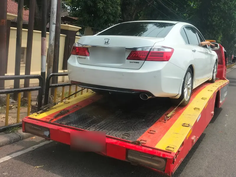 Mobil Honda putih berada di atas kendaraan derek flatbed