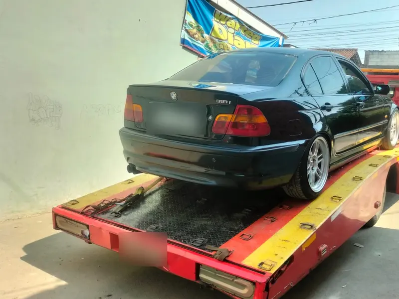 BMW hitam di atas flatbed untuk pemindahan kendaraan