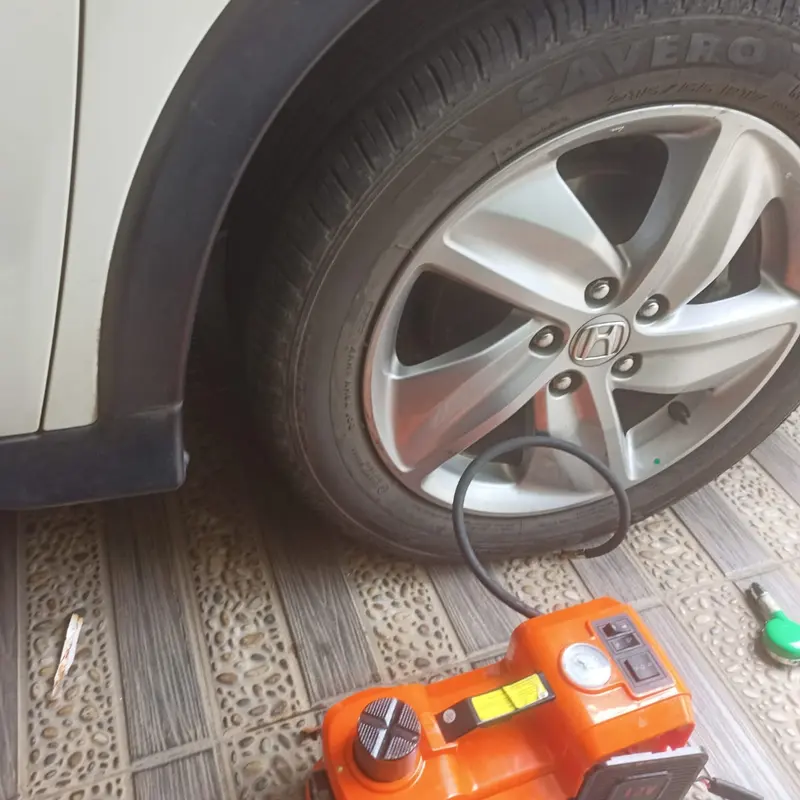 Kompresor portabel terhubung ke pentil roda mobil putih
