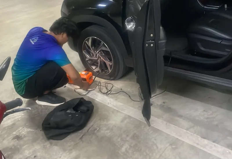 Teknisi AutoAman menggunakan kompresor di samping roda mobil